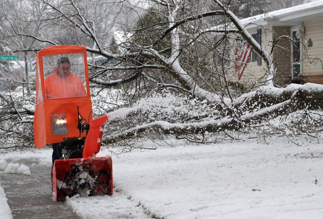 Mike Kuen clears heavy snow from his parents home after a large limb broke off a tree in their front yard along E. Florida Avenue during a spring snowstorm Wednesday, April 3, 2024, in Appleton, Wisconsin.
