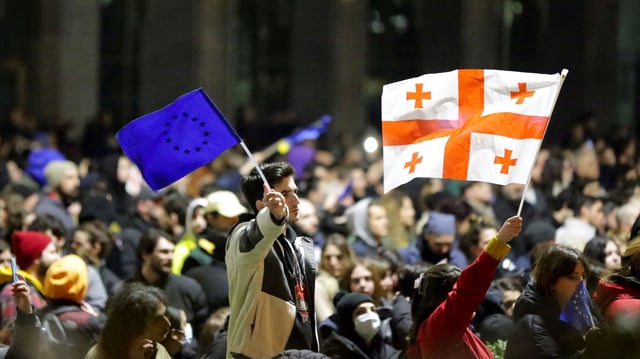 Protesters wave a Georgian flag and an EU flag as they rally against a draft law aimed at curbing the influence of "foreign agents" near the Georgian parliament building in Tbilisi, Georgia, March 9, 2023 (AP photo by Zurab Tsertsvadze).