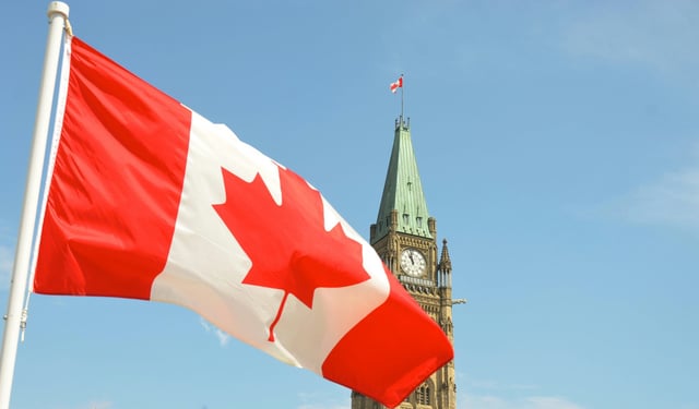 Canadian flag waving in front of the Parliament Building on Parliament Hill in Ottawa