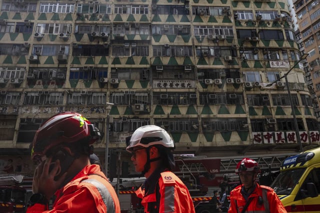 Firefighters walk past a building called New Lucky House where a fire started in Hong Kong, Wednesday, April 10, 2024.