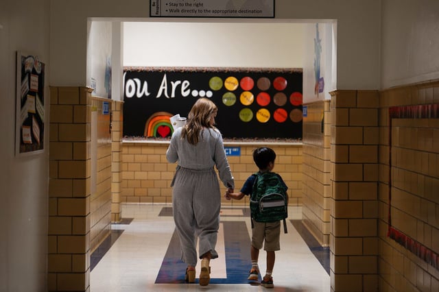 A teachers leads her student to English class at George Mason Elementary School in Alexandria, Virginia, in August 2023.