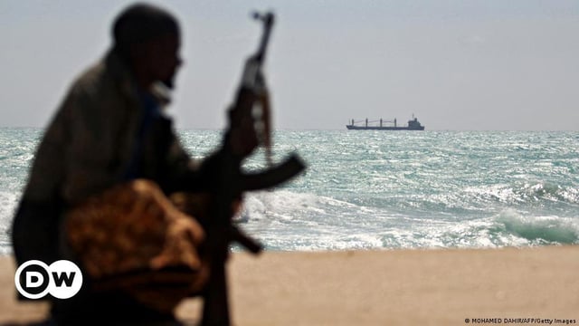 The silhouette of a Somali pirate looking at a ship on the horizon