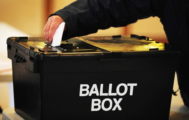 a voter placing a ballot paper in the ballot box at the polling station at Market Hall in Swadlincote, Derbyshire.