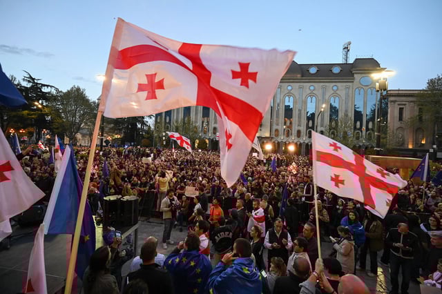 Georgian pro-democracy groups activists wave flags of Georgia and are wrapped in flags of Europe as they protest against a "foreign influence" bill outside the parliament in Tbilisi on April 15, 2024.