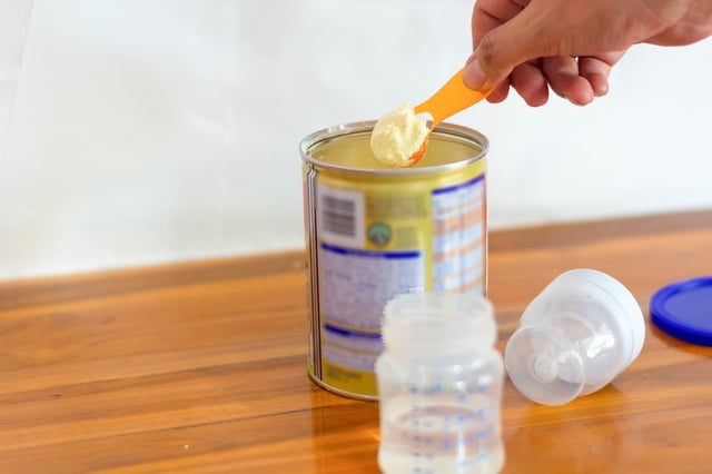 Preparation of mixture baby feeding on wooden background. 