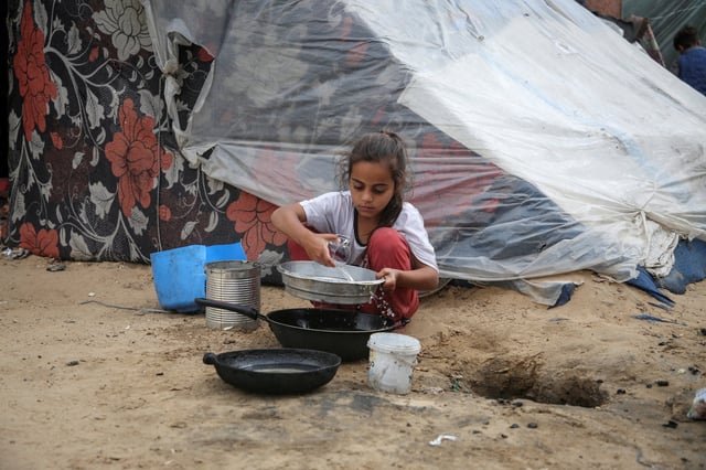 A girl pours water next to a tent in Rafah, southern Gaza on Saturday. Photo: Reuters