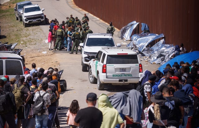 Border Patrol officers work to sort out migrants gathered between the primary and secondary border fences between Mexico and the United States in San Diego. REUTERS/Mike Blake