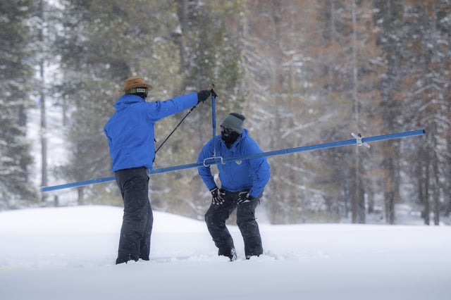 Sean de Guzman, right, snow survey manager for the Department of Water Resources, measures the snow with the help of DWR engineer Jacob Kollen for the final snow survey of the season at Phillips Station on April 3, 2023. A new study finds the snow deluge in California, which quickly erased a two decade long megadrought, was essentially a once-in-a-lifetime rescue from above. The study authors coined the term “snow deluge” for one-in-20-year heavy snowfalls. (Hector Amezcua/The Sacramento Bee via AP, File)