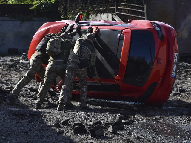 Ukrainian servicemen turn over a damaged car at the scene of a Russian missile attack in Zaporizhzhia, Ukraine, Wednesday, May 8, 2024. (AP Photo/Andriy Andriyenko)
