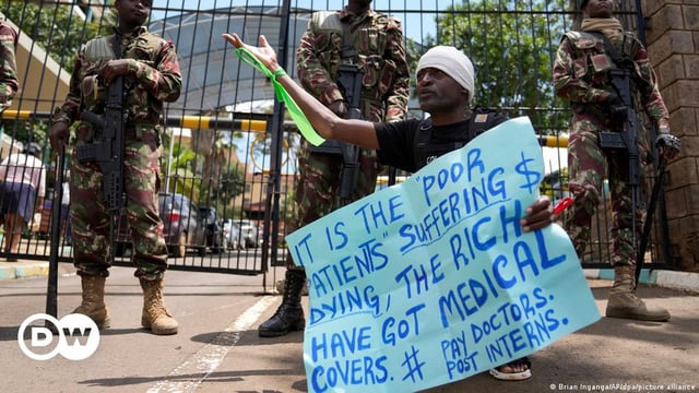 A protester is watched by police in Nairobia, Kenya
