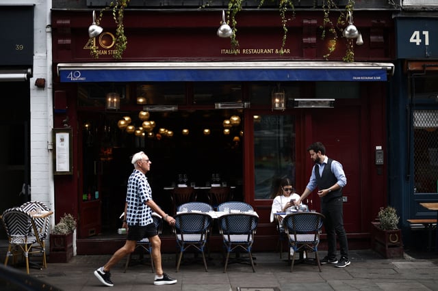 A customer is served outside an Italian restaurant in the Soho area of London on June 18, 2023. Recent data showed UK inflation slowed to a 13-month low in April, but remains elevated at 8.7 percent as soaring food prices offset weaker energy costs. (Photo by HENRY NICHOLLS / AFP) (Photo by HENRY NICHOLLS/AFP via Getty Images)