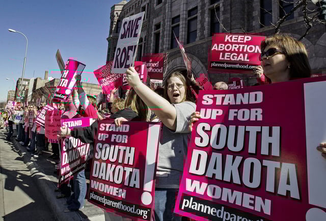 Demonstrators hold up signs as they protest South Dakota's new anti-abortion law outside the Federal Court building in Sioux Falls, S.D., on March 9, 2006.
