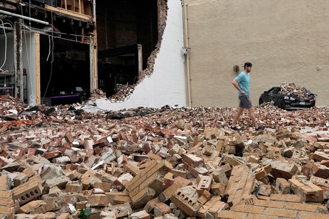 A man walks through fallen bricks from a damaged building in the aftermath of a severe thunderstorm in Houston on Friday, May 17, 2024. Thunderstorms pummeled southeastern Texas on Thursday, killing at least four people, blowing out windows in high-rise buildings and knocking out power to more than 900,000 homes and businesses in the Houston area.