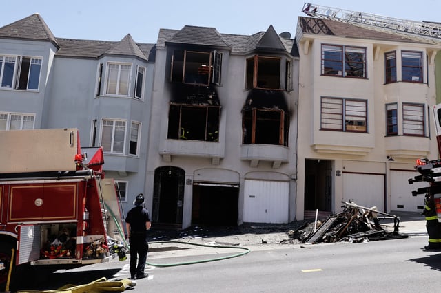 A firefighter stands in front of a home at the scene of an earlier house fire on Grove Street where a dog walker recently targeted by racist threats lives on Tuesday, May 21, 2024 in San Francisco, Calif.