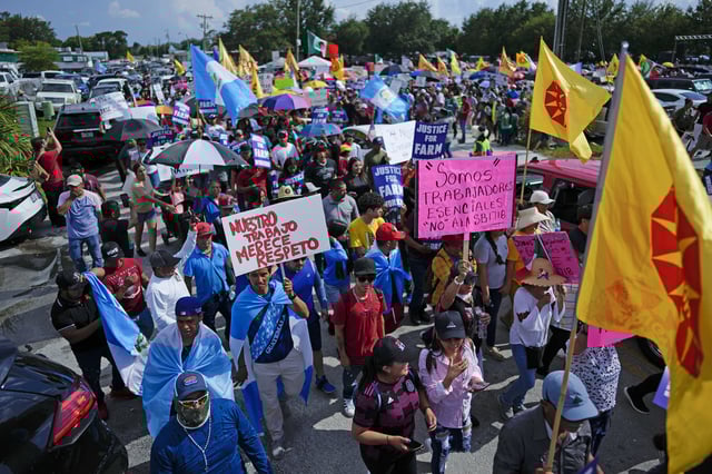 People carry signs that read "Our work deserves respect" and "We are essential workers; No to SB1718" as hundreds gathered to protest peacefully against Florida Senate bill 1718, which imposes restrictions on undocumented immigrants on June 1, 2023, in Immokalee, Fla.