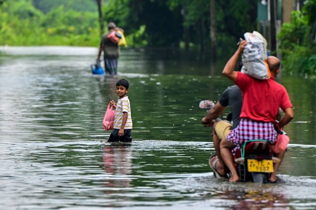 Residents make their way through a flooded street after heavy rains on the outskirts of Colombo in May. Photo: AFP