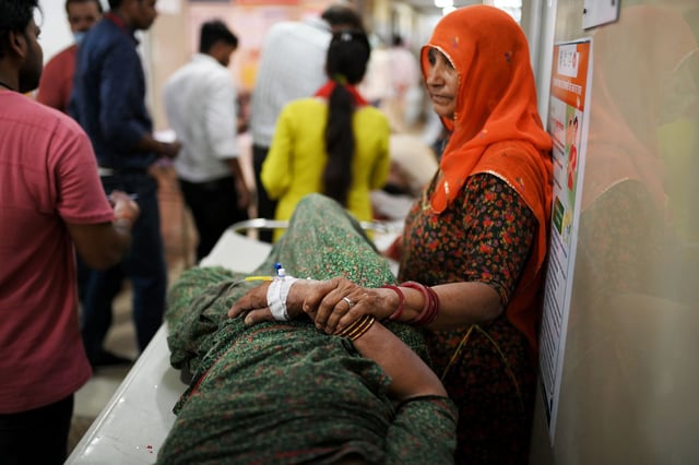 A woman is standing beside her family member who is suffering from heatstroke in Varanasi, India, on May 30, 2024.