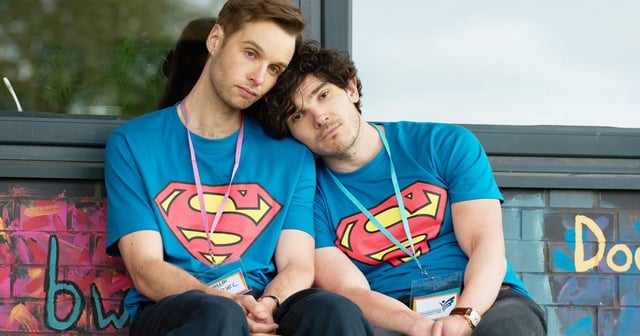 Gabriel and Andy wearing Superman t-shirts, sitting next to one another, with their heads leaning on one another