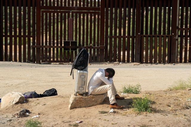 An asylum-seeking migrant from China rests on a rock while waiting to be transported by the US Border Patrol after crossing the border from Mexico into the in Jacumba Hot Springs, California, on June 4.