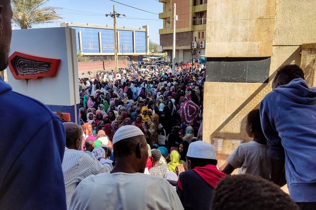 People from states of Khartoum and al-Jazira, displaced by the ongoing conflict in Sudan between the army and paramilitaries, queue to receive aid from a charity organisation in Gedaref on December 30, 2023.