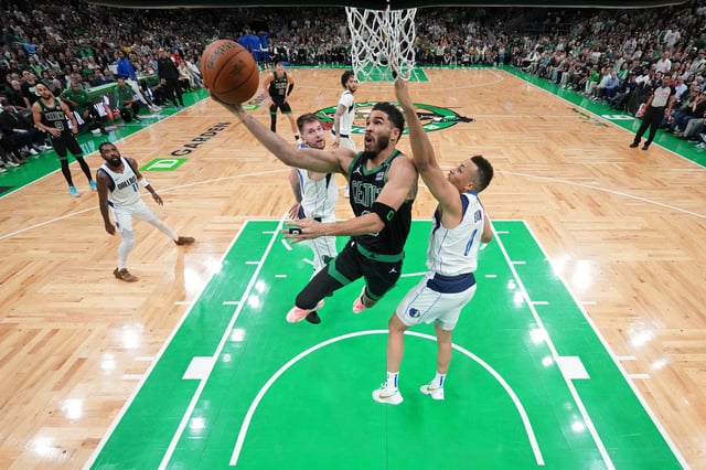 Boston Celtics forward Jayson Tatum (center) drives against Dallas Mavericks guard Luka Doncic (left) and guard Dante Exum (right) during Game 2 of the 2024 NBA Finals at TD Garden.