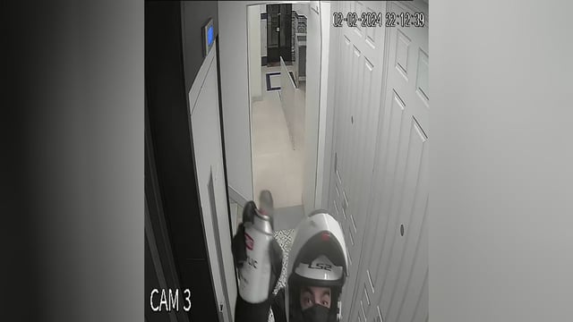 Security camera footage shows a man in a motorcycle helmet, who investigators allege is David Knezevich,  spray painting a security camera at Ana Henao's Madrid apartment on February 2, 2024.