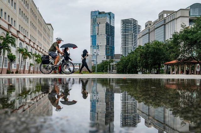People are reflected in puddles of rain in West Palm Beach, Fla., on June 11, 2024.