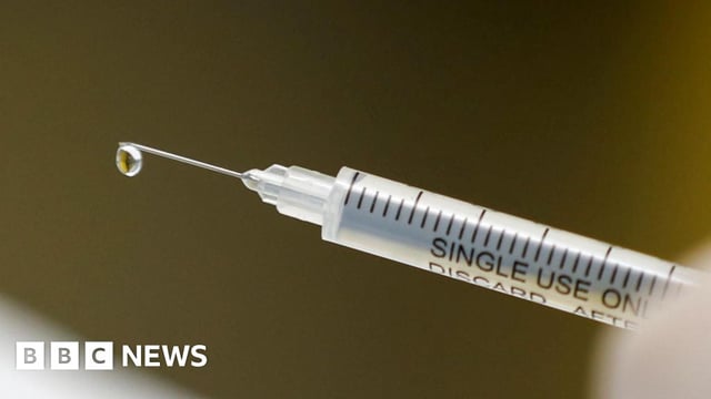 Close-up of a syringe with droplet at needle tip