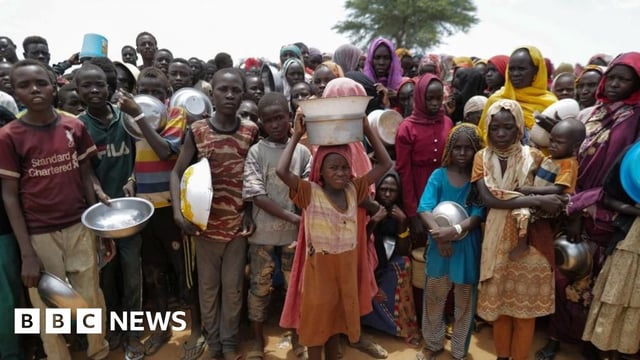 Sudanese children line up to receive rice portions from Red Cross volunteers