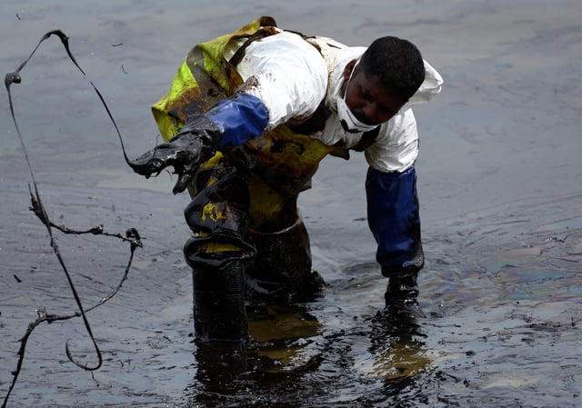 A worker operates a vacuum system during the clean-up of an oil slick in Sentosa, Singapore. Photo: Reuters