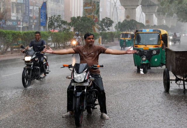 A man reacts during rainfall as the temperature dips in the Indian capital upon the arrival of monsoon, which was struggling with heatwave in the past weeks, in New Delhi, India on Thursday. Photo: Reuters