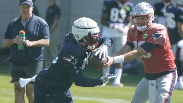 New England Patriots' Ezekiel Elliott takes a handoff from quarterback Mac Jones during practice for NFL football training camp Wednesday, Aug. 16, 2023, in Green Bay, Wis. (AP Photo/Morry Gash)