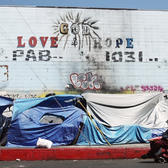 LOS ANGELES, CALIFORNIA - JUNE 28: A person passes an encampment of unhoused people in the Skid Row community on June 28, 2024 in Los Angeles, California. The U.S. Supreme Court ruled today that cities can ban people, including those who are homeless, from camping and sleeping outdoors in public places, overturning lower court rulings. Skid Row is home to thousands of people who are either experiencing homelessness on the streets or living in shelters.