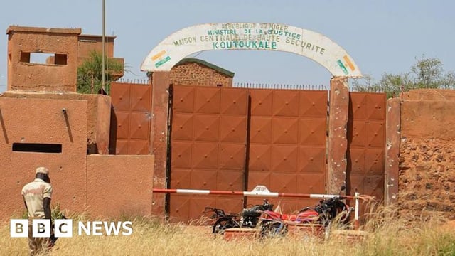 A Nigerien soldiers walks near calcined motorcycles used by assailants, in front of the the prison of Koutoukale, near Niamey, following an attack on October 17, 2016.