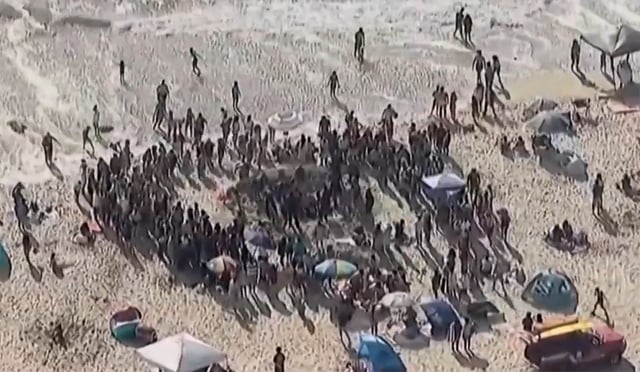 Lifeguards rescue teen girl stuck in sand at Mission Beach, drawing crowd.