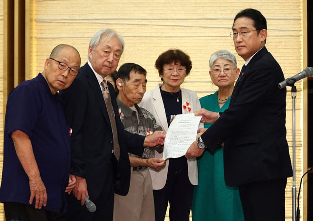 Japan's Prime Minister Fumio Kishida (R) receives a demand letter from the plaintiffs in the forced sterilization lawsuit at the prime minister's office in Tokyo on July 17, 2024.