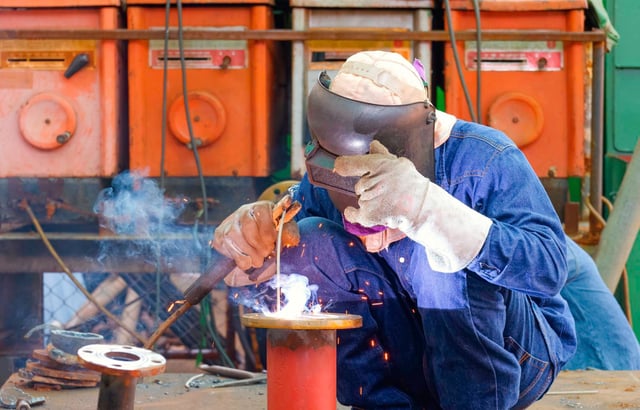 Welder is welding metal flange to connect with steel pipe for improving oil pipeline system work