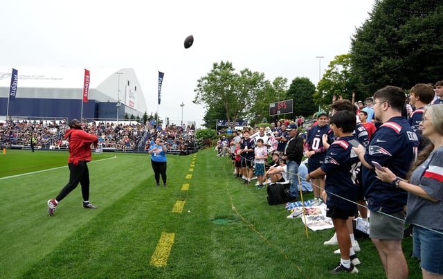 Patriots linebacker Matthew Judon tosses a football into the crowd playing catch with New England Patriots fans before the official start of practice on Wednesday morning. Patriots first day of training camp at Gillette on July 24, 2024.
