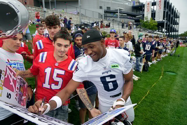 Cameron Carreiro of East Providence, RI watches in awe as New England Patriots, 4th round draft pick, wide receiver Javon Baker, stopped pre-practice to adds his autograph to a poster Cameron made chronicling Baker's football career so far.