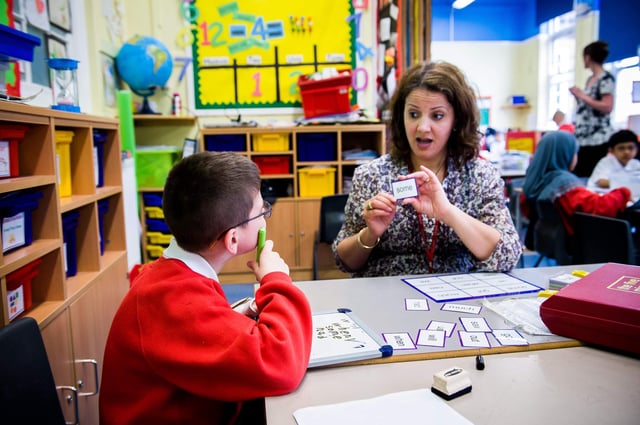 A learning support assistant with Special educational needs and Disability (SEND) child in a UK classroom. Photo: Roger Askew / Alamy