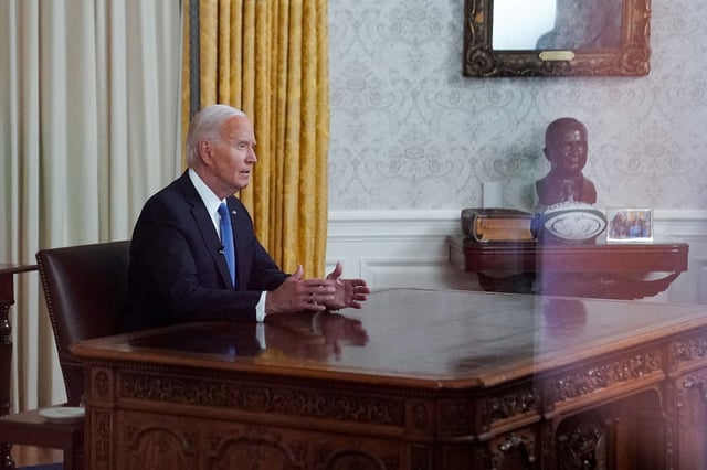 U.S. President Joe Biden is seen through a window as he delivers an address to the nation on his decision to end his reelection campaign, from the Oval Office of the White House in Washington, U.S., July 24, 2024.