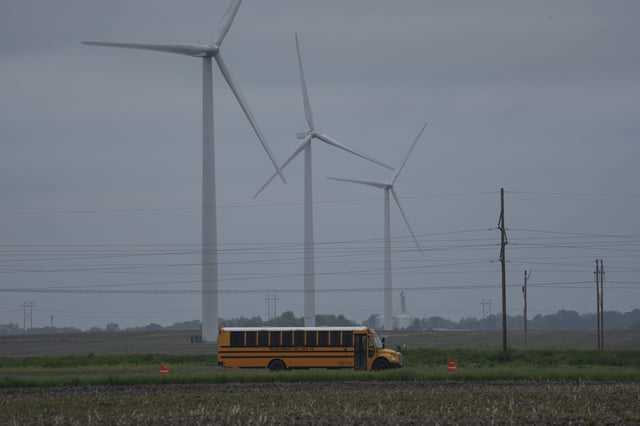 A school bus drives down a road near a field of wind turbines, Thursday, May 9, 2024, in Paxton, Ill. (AP Photo/Joshua A. Bickel)