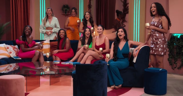 The cast of Love Is Blind girls looking shocked and smiling as they sit down in the communal pod area.
