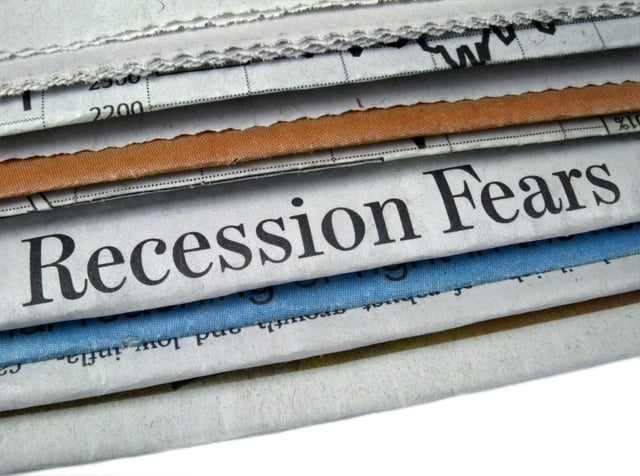 A staggered stack of financial newspapers with one visible headline that reads Recession Fears.