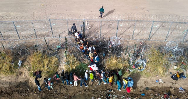 In an aerial view, immigrants pass through coils of razor wire while crossing the U.S.-Mexico border on March 13, 2024 in El Paso, Texas. (John Moore / Getty Images)