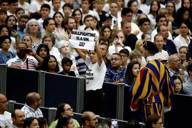 A PETA activist holds a banner reading in English: "Bullfight is sin", during the weekly general audience in Paul VI hall at the Vatican, August 7, 2024. REUTERS/Guglielmo Mangiapane REFILE - CORRECTING LOCATION FROM "SAINT PETER'S SQUARE" TO "PAUL VI HALL".