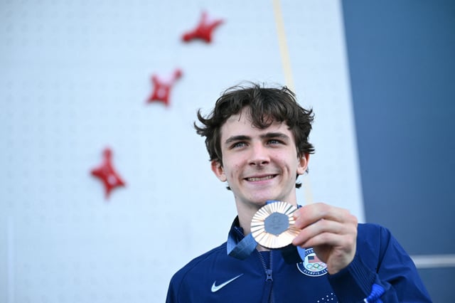 Bronze medalist Sam Watson poses on the podium of the men’s sport climbing speed event during the Paris Olympics on August 8, 2024.