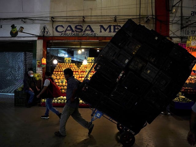 FILE - A porter hauls a load of crates at the Central de Abastos, the largest wholesale food and goods market, in Mexico City, Aug. 3, 2022.
