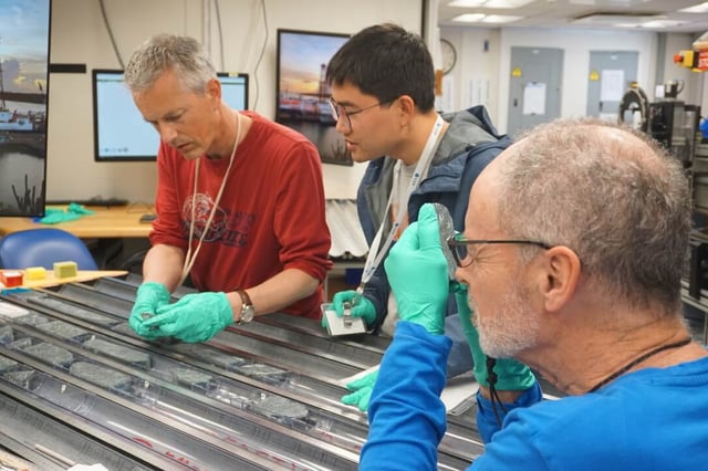 Professor Johan Lissenberg (left) and colleagues analyzing the cores, which were recovered from a “tectonic window” on the Mid-Atlantic Ridge. (Credit: Lesley Anderson, Exp. 399, JRSO_IODP)