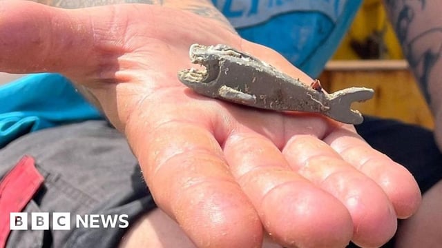 Richard West's open hand in which lies the sea-worn grey Lego shark